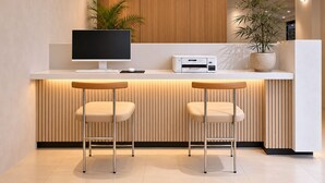 Une cuisine moderne dotée d’un îlot central intégré, d’un ordinateur de bureau, d’une imprimante, de deux tabourets de bar et de plantes en pot.