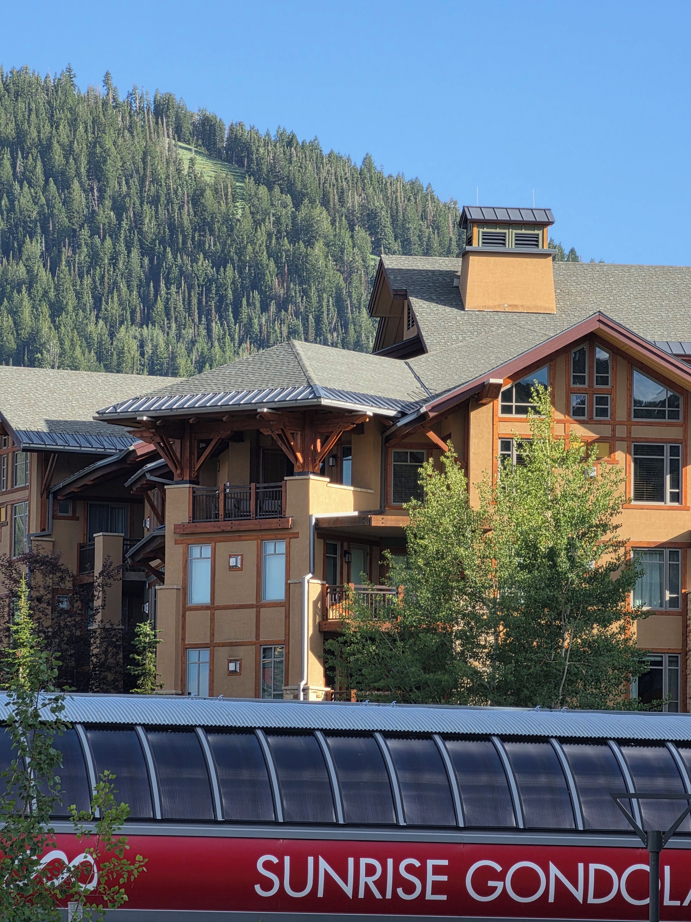 A multi-story building with a sloped roof, large windows, and a balcony.