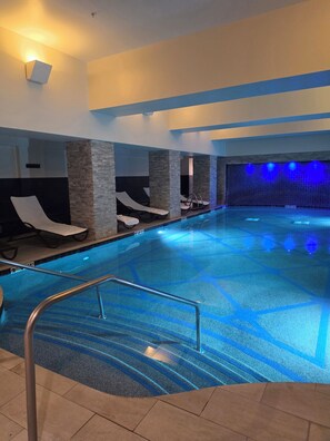 An indoor swimming pool with lounge chairs and a blue-lit wall. - Park city Utah 2BR/2BA lock off unit Ski in Ski out. *Forbes 4 Diamond Resort. 
 (Park City)