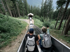 A person in a metal slide with a backpack, surrounded by a forested area. - Panorama Apartment Monte Central (Neukirchen am Grossvenediger)