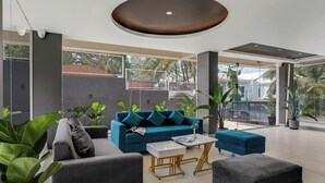 Una sala moderna con un sofá azul, sillones grises y una mesa de centro.