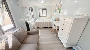 Une pièce de taille modeste comprenant un canapé, un lit, une commode et une fenêtre.