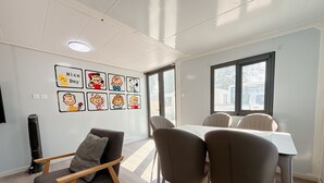 Un coin repas avec une table et des chaises, un mur décoré de posters de personnages de dessins animés et une fenêtre donnant sur l’extérieur.