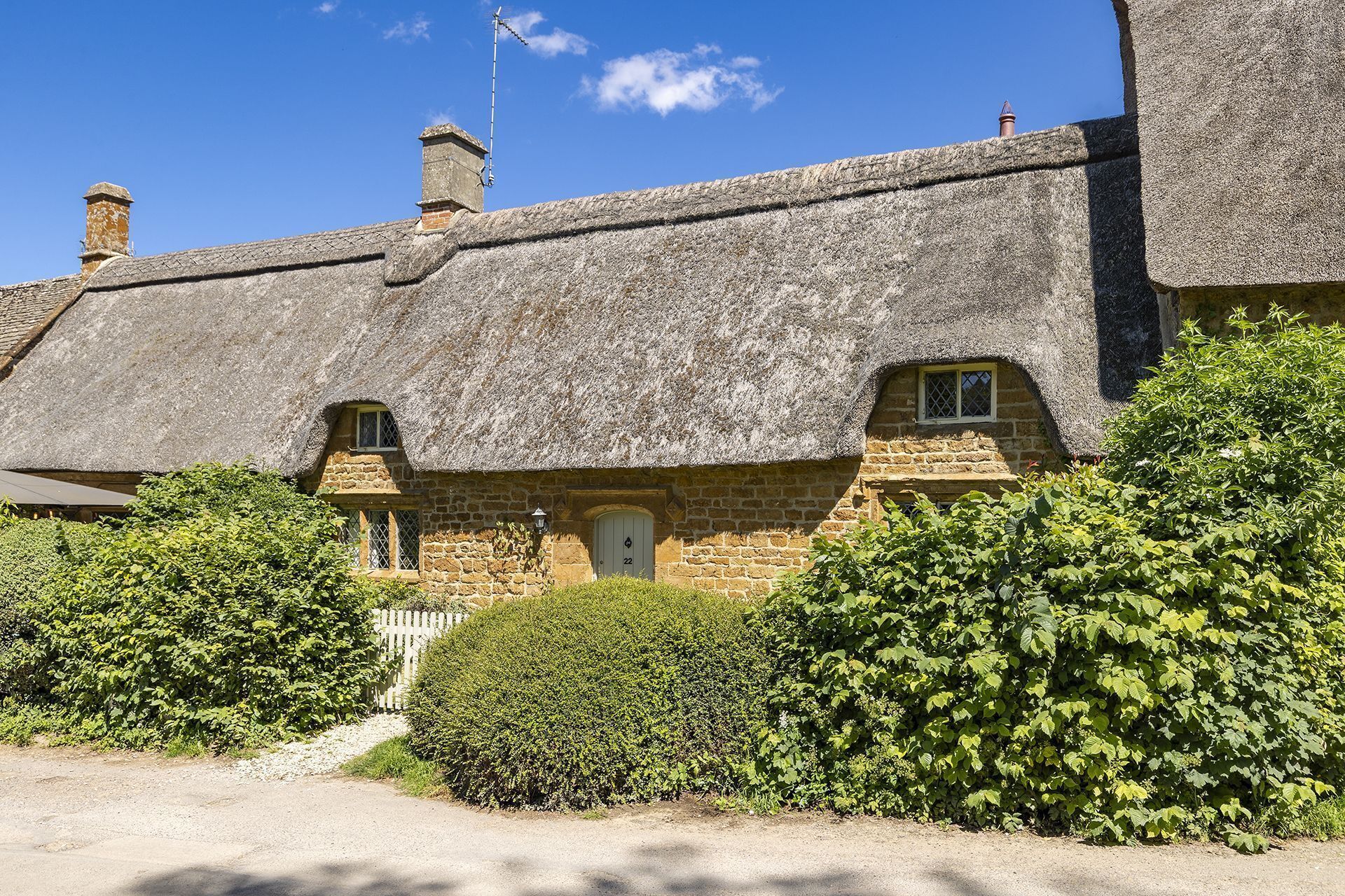Ein traditionelles Steinhaus mit Strohdach, einem kleinen Fenster und einer Tür mit der Nummer 22.