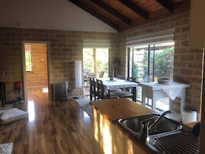 A kitchen with a wooden countertop, a sink, and a dining area with chairs and a table.