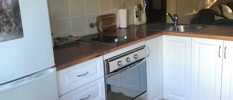A kitchen with white cabinets, a built-in oven, a refrigerator, and a sink.