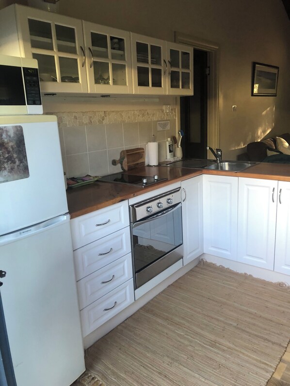 A kitchen with white cabinets, a built-in oven, a refrigerator, and a sink.