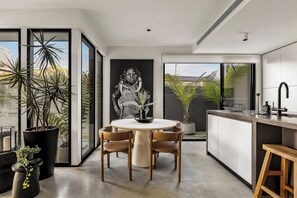 Una cocina moderna con comedor, ventanas amplias y plantas en macetas.