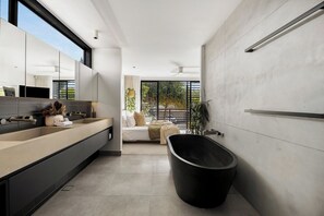 Un baño moderno con un espejo grande, una bañera negra y un ventanal con vistas al verdor.