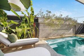A pool area with lounge chairs and tropical plants. - Luxury Villas Urban Tropic (Gold Coast)