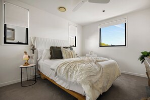Une chambre à coucher avec un lit, une table de chevet, une lampe et une fenêtre.