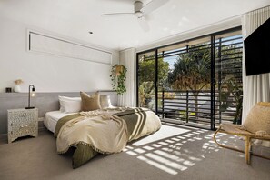 Un dormitorio con cama, mesita de noche y un ventanal con vistas a zonas verdes.