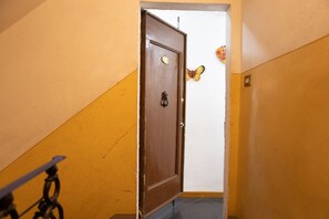 A narrow hallway with a wooden door, a butterfly decoration on the wall, and a bicycle leaning against the wall. - San Frediano Nest Apartment (Florence)