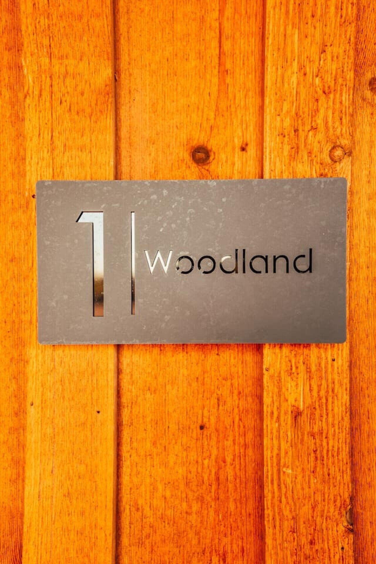 Une plaque métallique portant le chiffre « 1 » et le mot « Woodland », le tout sur un fond en bois.