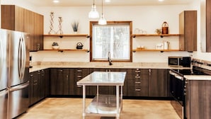 A modern kitchen with dark wood cabinets, stainless steel appliances, and a central island.