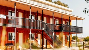 A two-story wooden building with a covered porch, a staircase, and a sign indicating 'ZING TRAILS Suites.'