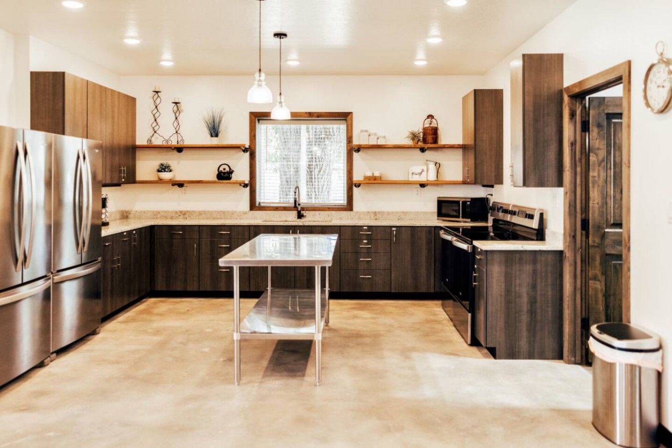 A modern kitchen with stainless steel appliances, dark wood cabinets, and a central island.