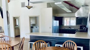 A modern kitchen with a central island, wooden dining table, and chairs. - Dino Trails Getaway South - Sleeps up to 42 People (Jensen)