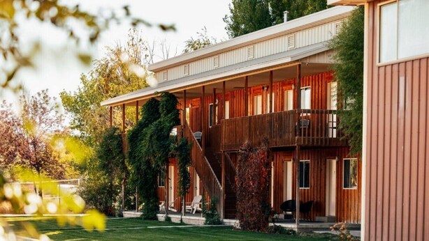 A modern building with a covered outdoor area, a staircase, and a well-maintained lawn. - Dino Trails Getaway South - Sleeps up to 42 People (Jensen)