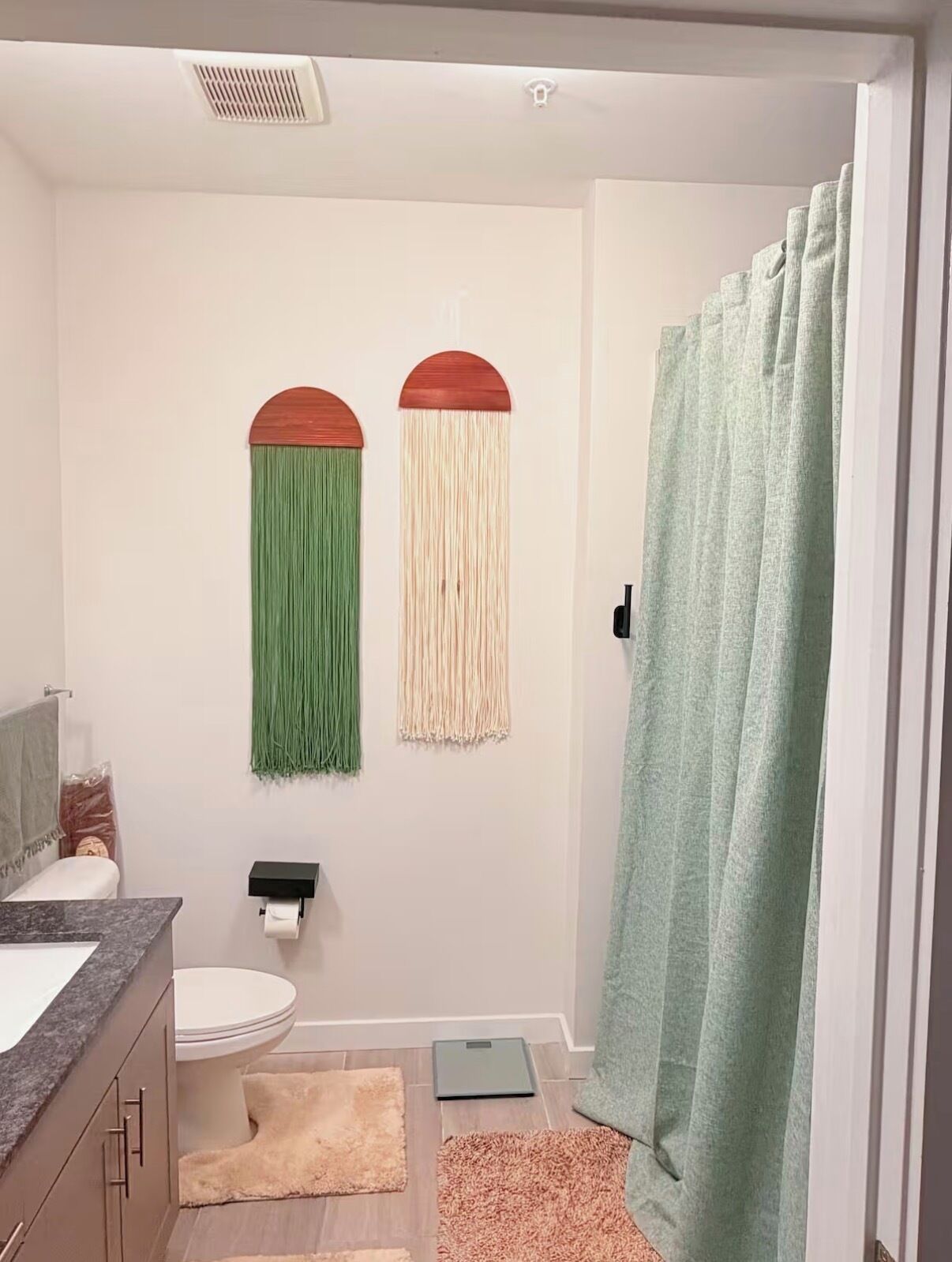 Un baño con inodoro, lavamanos, cortina de ducha y una balanza en el suelo.