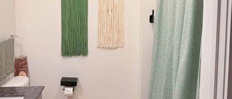 Un baño con inodoro, lavamanos, cortina de ducha y una balanza en el suelo.