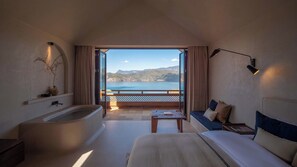 A hotel room with a large bathtub, a sofa, a small table, and a view of the sea. - lugu Lake Cheman Ruyingsong Mid Hotel (Lijiang)
