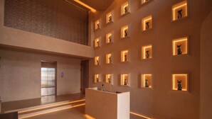 Un vestíbulo moderno con una recepción, una escalera y una pared con vitrinas iluminadas.