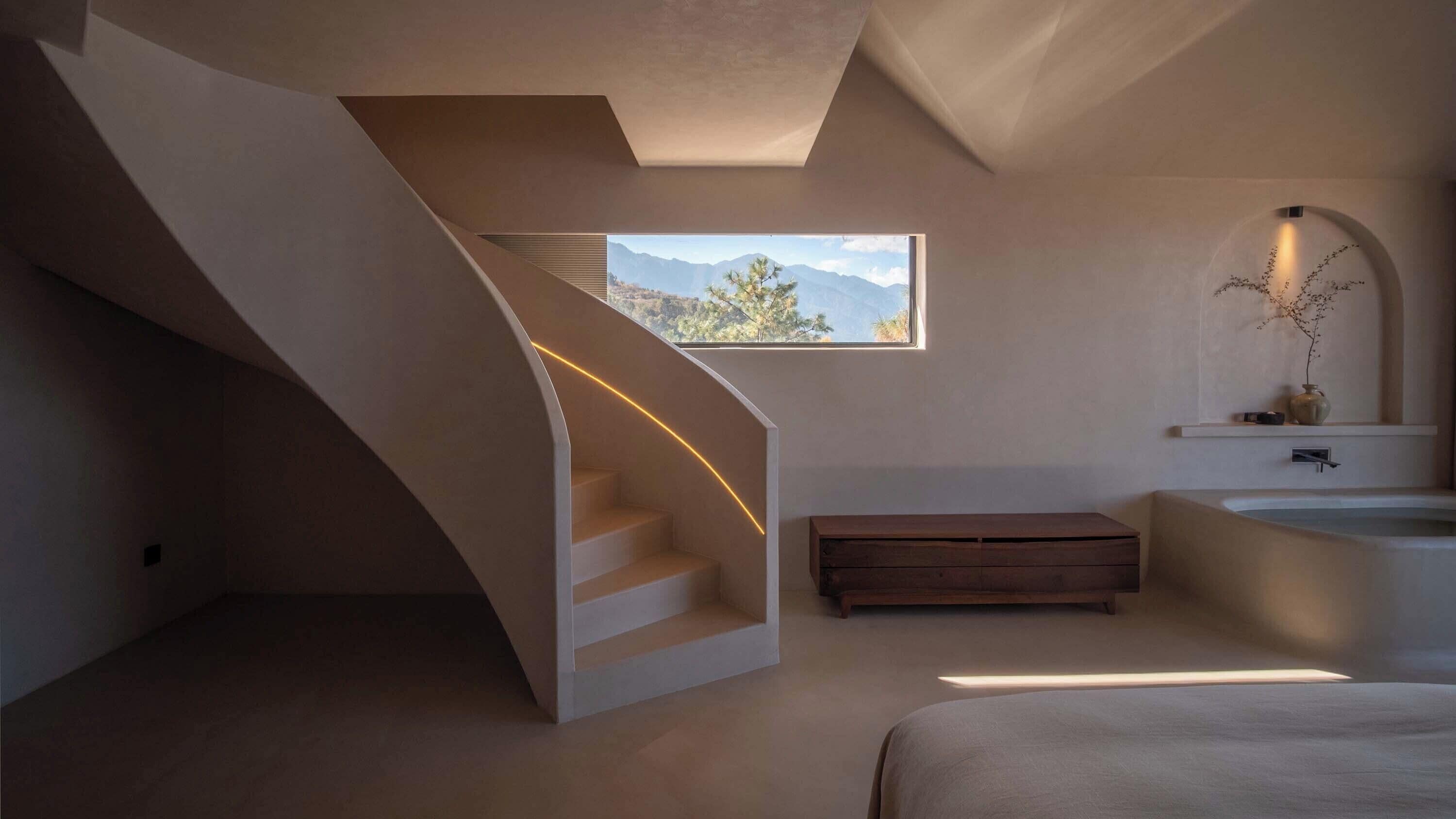 Un interior moderno con una escalera curva, vistas a montañas, una bañera y un banco.