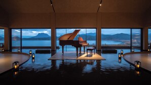 Un piano de cola en una habitación amplia con ventanas grandes que dan a un paisaje pintoresco.