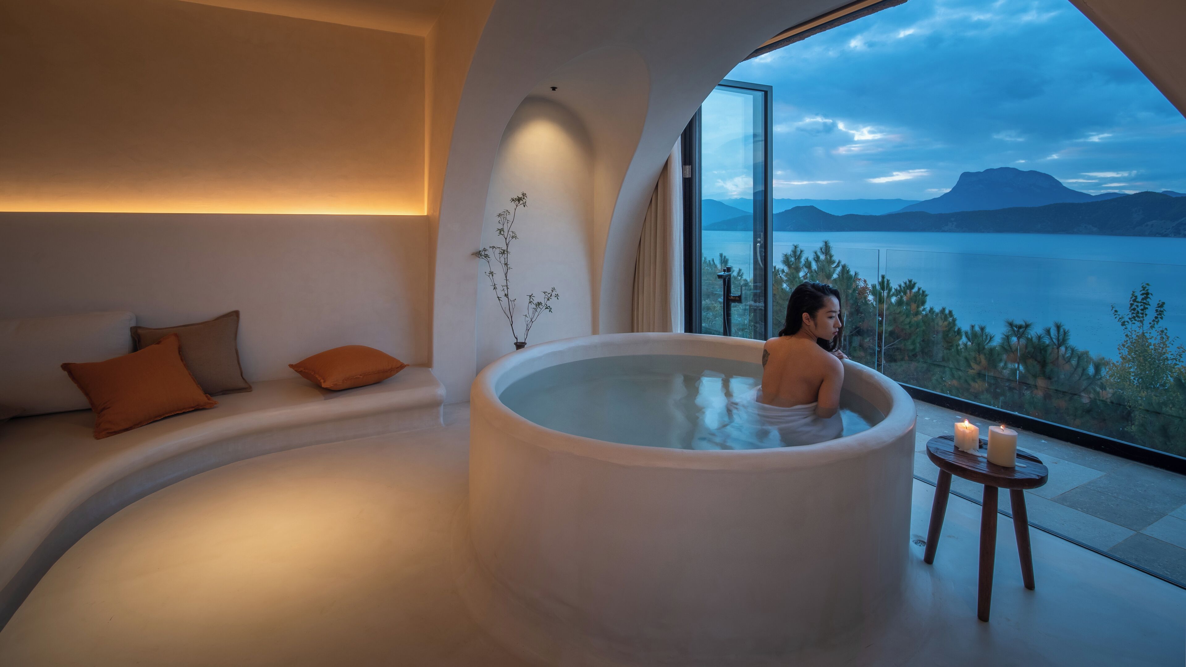 Una persona en un jacuzzi con vistas a un lago y montañas.