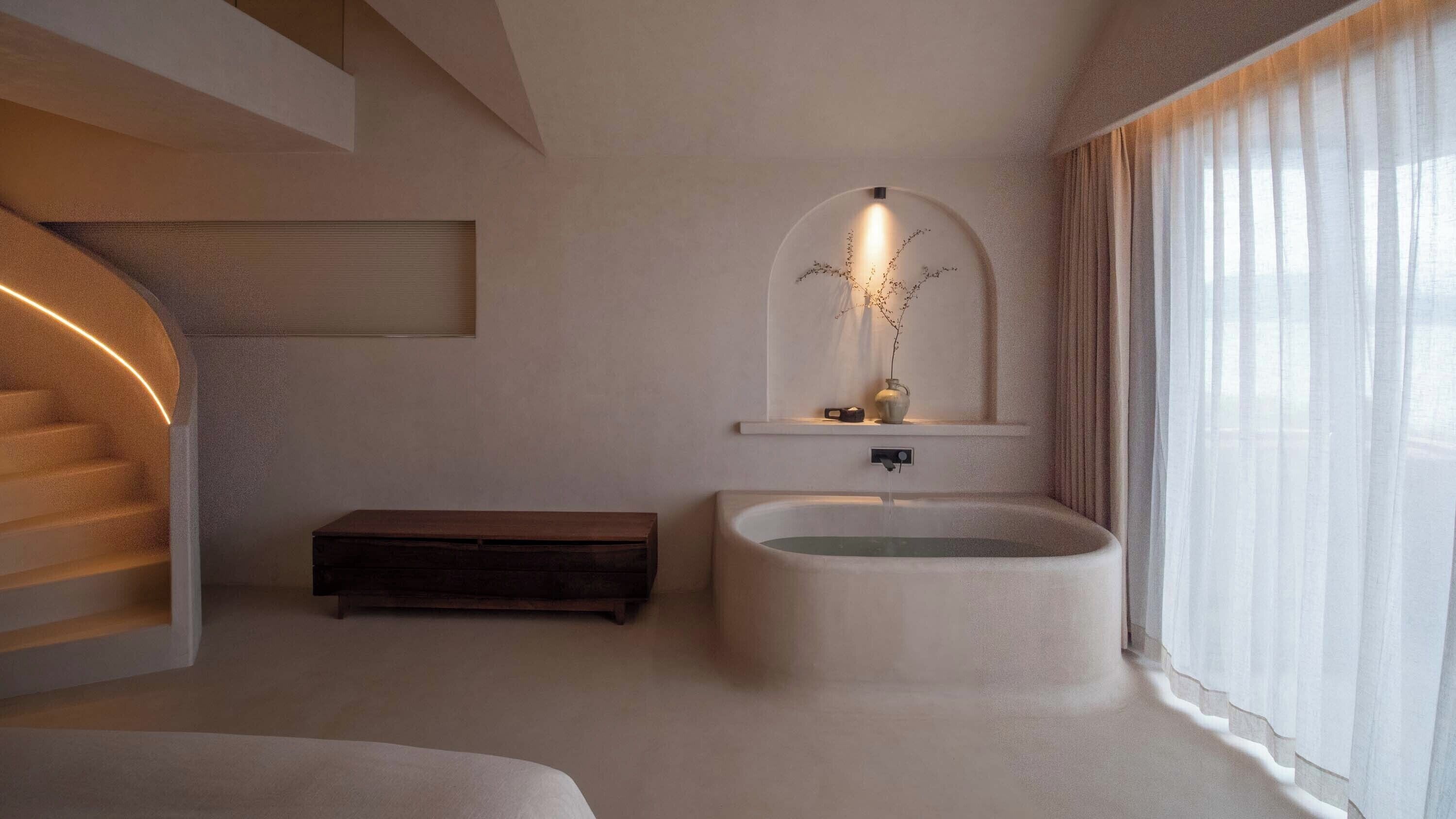 Un baño moderno con una bañera independiente, un estante pequeño con un florero y una escalera.
