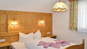 Un lit en bois avec du linge de lit blanc et deux lampes fixées au mur.