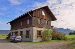 Une maison en bois à deux étages, avec une voiture garée devant.