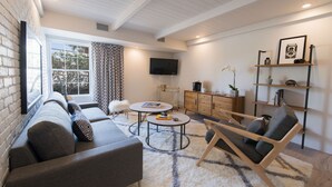 Una sala de estar moderna con sofá, sillón, mesa de centro y televisor.