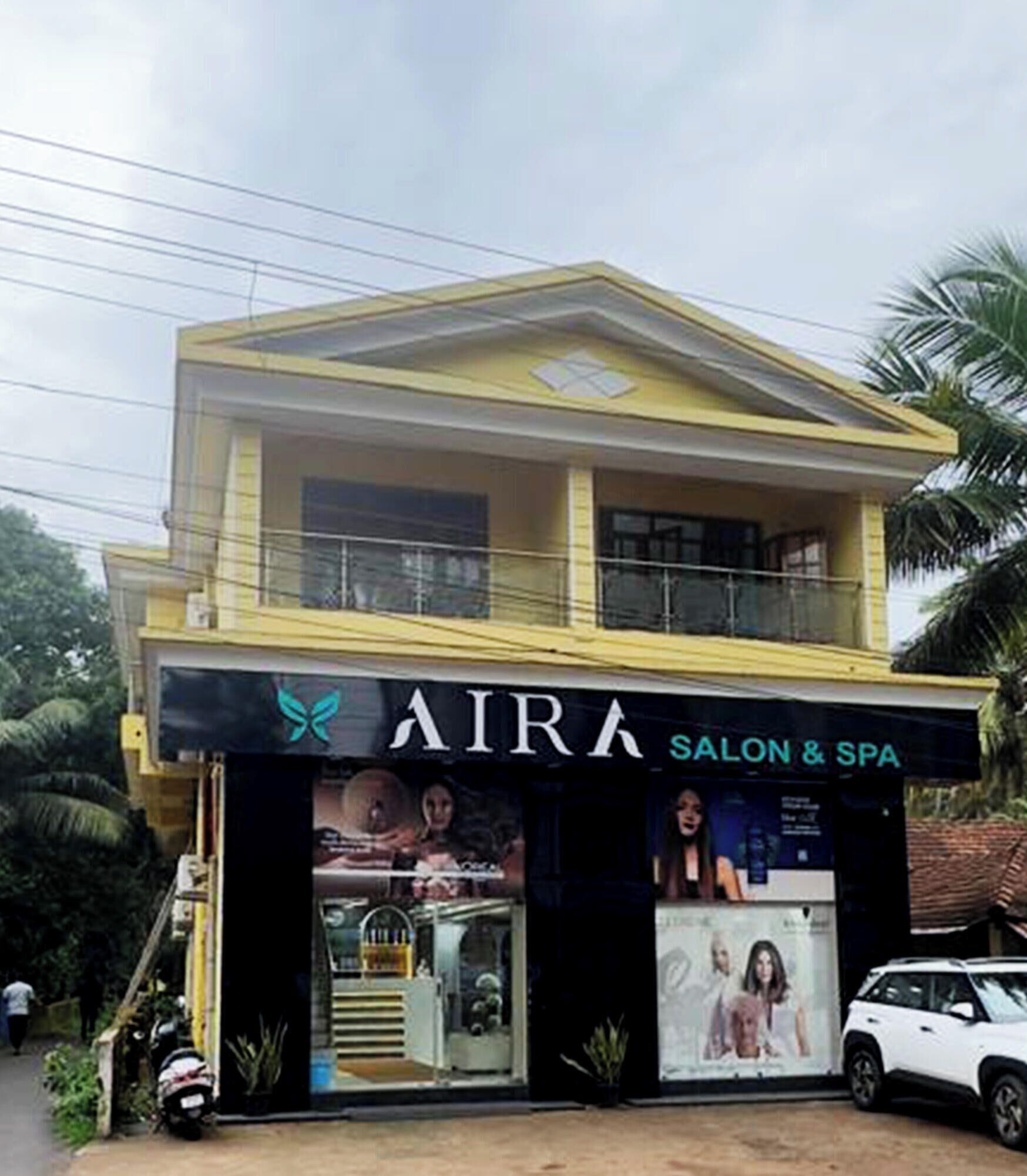 Un bâtiment à deux étages, avec une enseigne indiquant « AIRA SALON & SPA » au rez-de-chaussée.