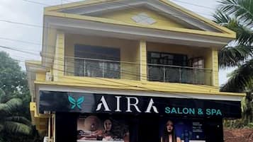 Un bâtiment à deux étages, avec une enseigne indiquant « AIRA SALON & SPA » au rez-de-chaussée.