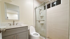 Ein Badezimmer mit Toilette, Waschbecken, Spiegel und einer Duschkabine.
