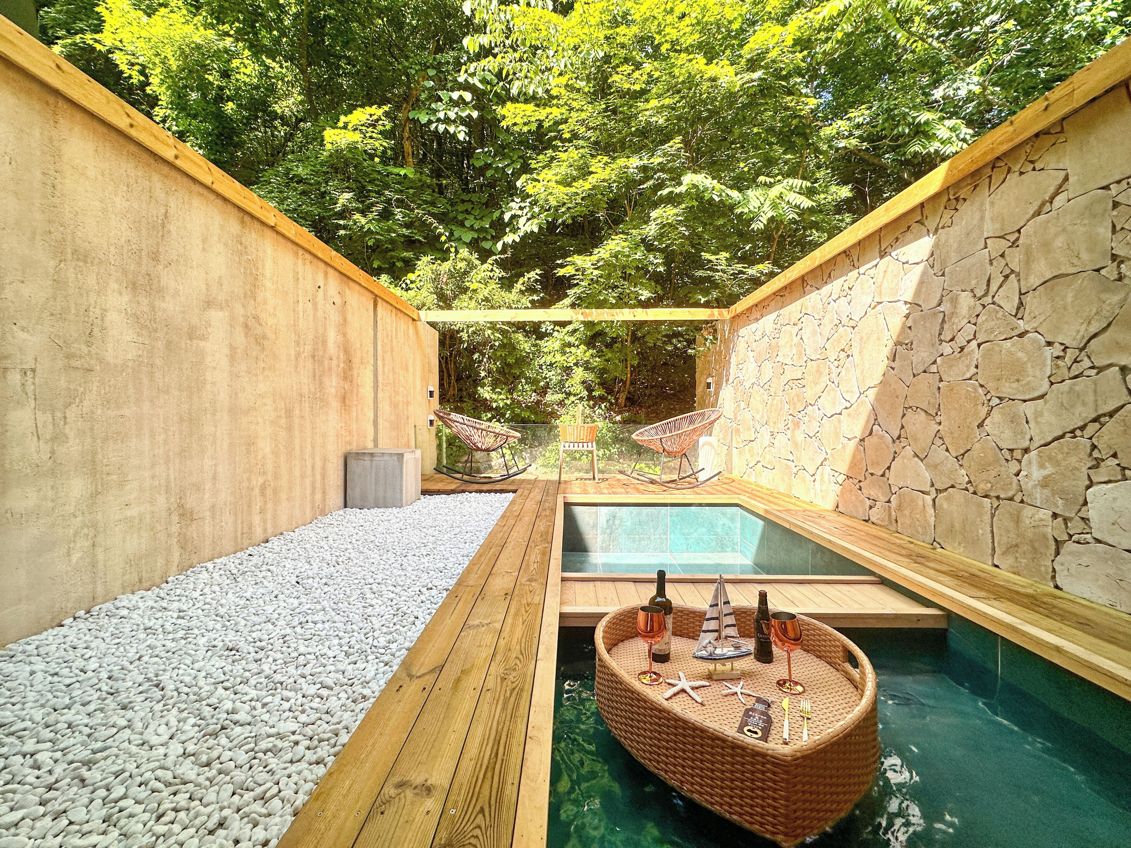 Un espacio de spa con una terraza de madera, una piscina pequeña y una zona de estar con una silla de mimbre.