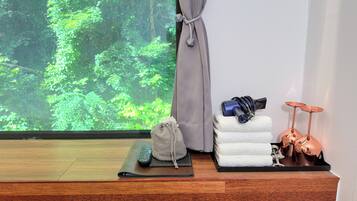 Ein Zimmer mit Blick auf einen Wald, ein Holztisch mit Fernbedienung, eine Yogamatte, ein Handtuch und ein Schlagzeug.