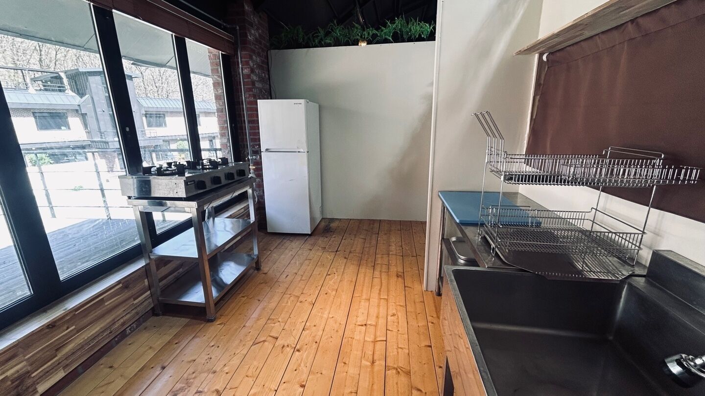 A compact kitchen with a wooden floor, a refrigerator, a stove, and a sink.