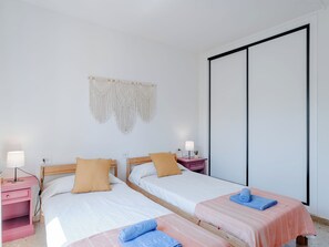 A bedroom with two beds, a macrame wall hanging, a wardrobe, and bedside lamps. - Apartment Cofisa by Interhome (Jávea)