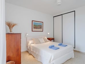 A bedroom with a bed, a nightstand, a wooden cabinet, a framed picture, and a wardrobe. - Apartment Cofisa by Interhome (Jávea)