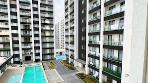 Un moderno edificio de apartamentos con piscina, mobiliario exterior y un jardín bien cuidado.