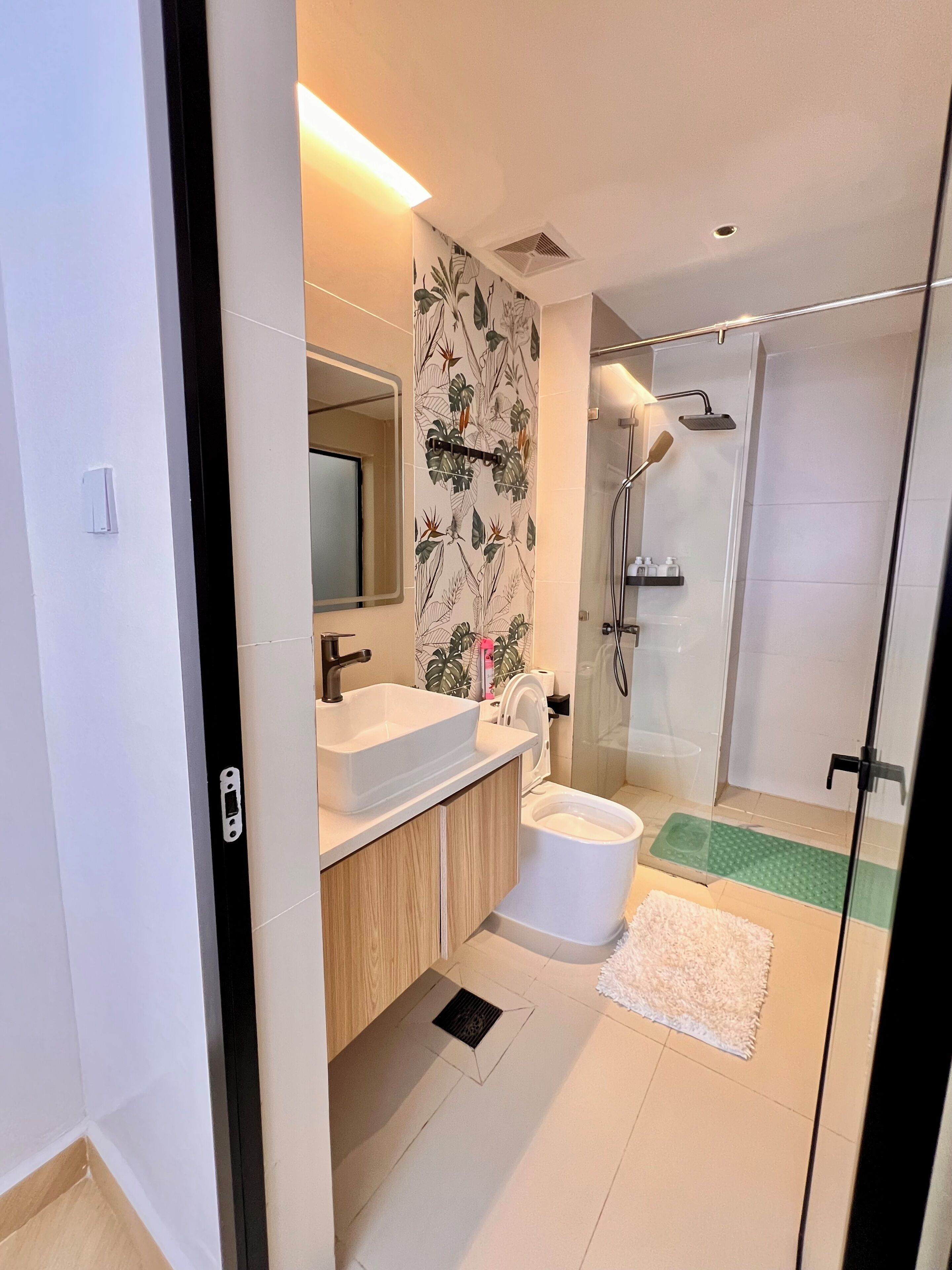 Une salle de bain moderne équipée d’un lavabo, de toilettes, d’une douche et d’un espace de douche clos par des parois de verre.