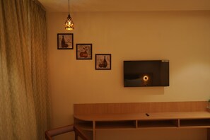 A room with a wooden bench, a TV mounted on the wall, and three framed pictures.