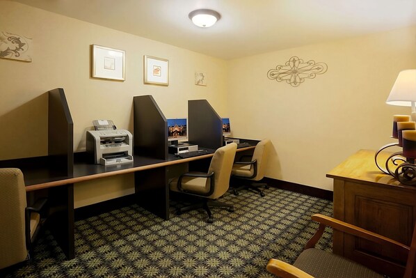 Ein Hotelbüro mit Schreibtischzellen, einem Drucker und einem Schreibtisch mit Lampe.