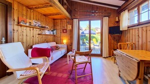 Un intérieur en bois comprenant un canapé, des fauteuils, une table et un téléviseur.