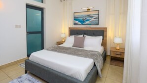 Un dormitorio con una cama, un cuadro sobre la cama y dos lámparas de noche.