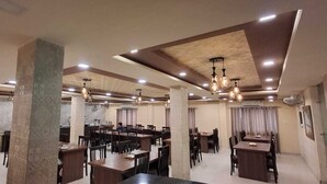 A spacious dining area with multiple tables and chairs, a bar area, and a modern ceiling design with recessed lighting. - MEERA MADHAV RESORT (Mathura)