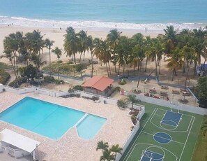 Ein Pool, ein Basketballplatz und ein Strand mit Palmen.